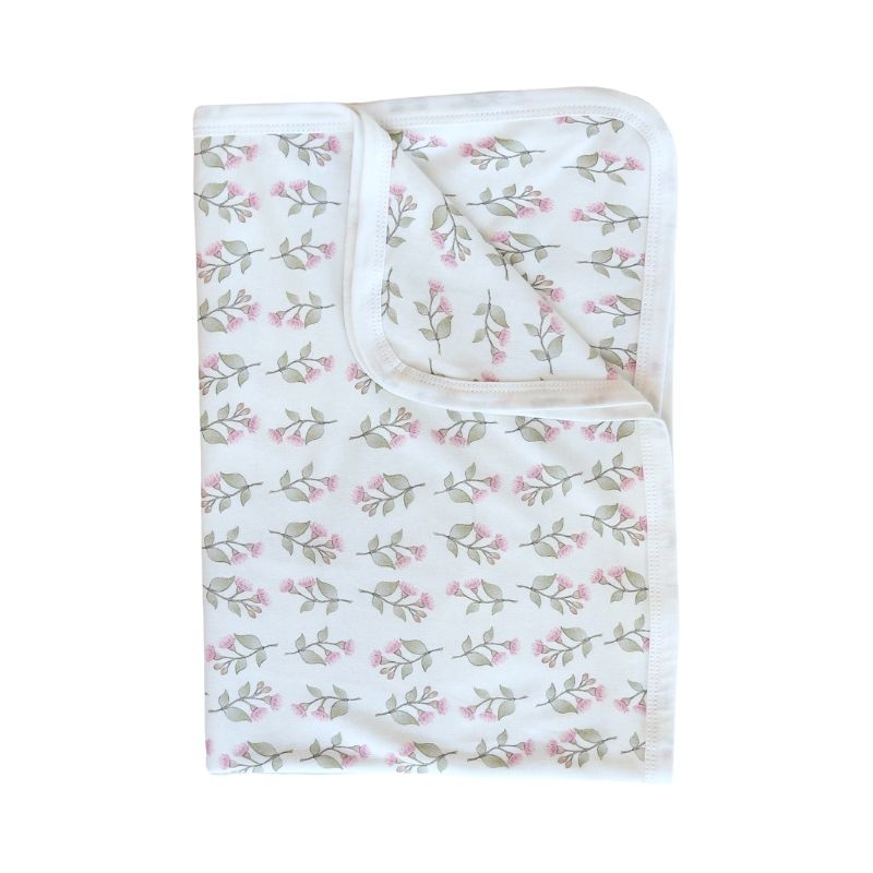 A white baby swaddle with blush and sage gum blossom pattern print, folded up with one corner folded down