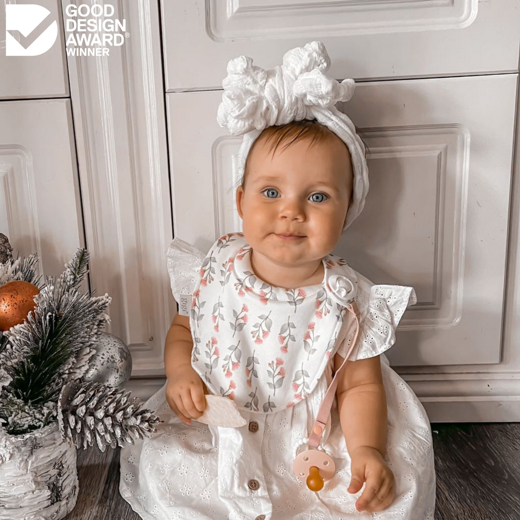 Girl in white dress wearing white bib with gum blossom pattern and a white headband